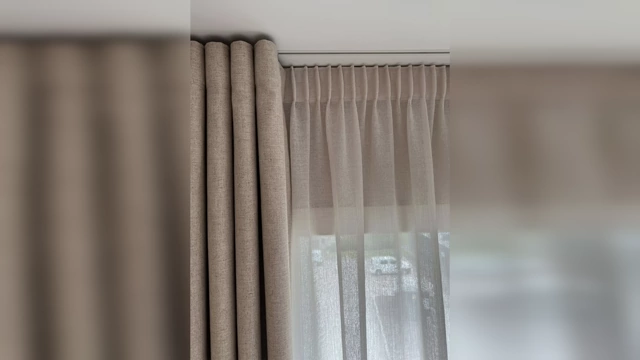 Close-up of elegant, natural-toned curtains with soft pleats, showcasing quality fabric and proper hanging.