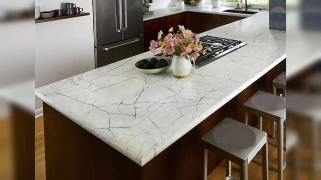 A kitchen countertop covered with faux marble contact paper, appearing artificial and lacking the depth of real stone.