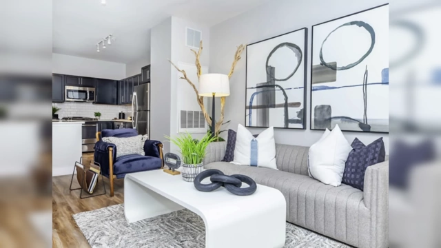 A model apartment living room with generic, large-scale abstract art and standard decor, lacking personal character.