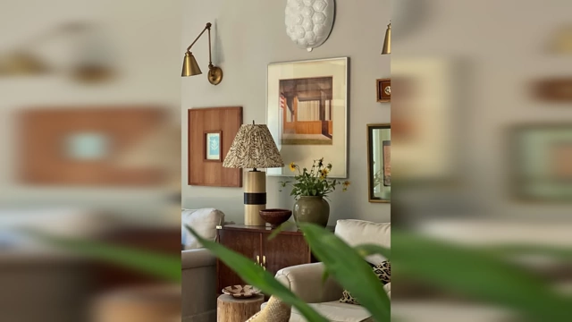 A corner of a room featuring a mix of vintage-style art prints, a unique lamp, and a textured vase, suggesting a curated and personal aesthetic.