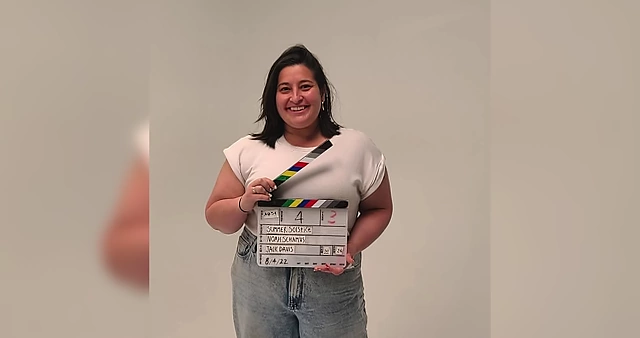 Harper holding a clapperboard, representing her freelance work producing shorts and feature films