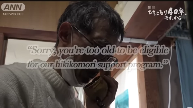 Text on screen reads, "Sorry, you're too old to be eligible for our hikikomori support program," over an image of an older man looking distraught, highlighting the age limitations of current support.