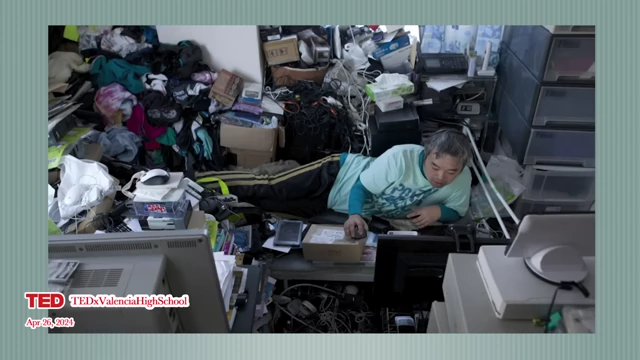 A man lies surrounded by clutter in his room, depicting the self-neglect often associated with hikikomori.