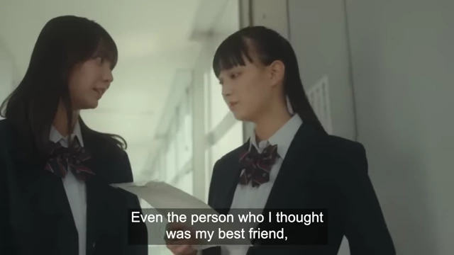 Two schoolgirls in uniform talk in a hallway, representing the social environment where bullying can occur.