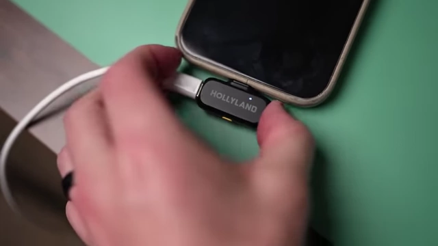 The HollyLand Lark A1 receiver plugged into a phone, with a charging cable also connected.