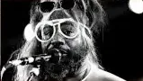 A black and white photo of George Clinton with large white framed glasses.