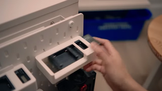 Camera battery chargers held in custom 3D printed holders on the SKADIS pegboard