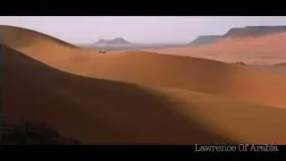 An extreme wide shot showing a vast desert landscape with tiny figures in the distance.
