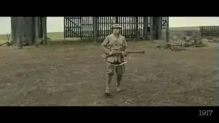 A full shot of a soldier standing in a desolate field with a gate in the background, showcasing his full body.