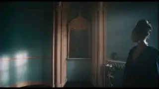 A dolly shot of a woman looking into a mirror, with the camera moving smoothly towards her.