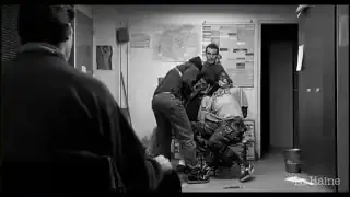 A static shot from "La Haine" showing characters interacting in a confined space, emphasizing a sense of stillness while action unfolds.