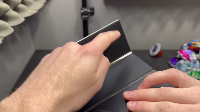 A hand points to the top edge of the folded Huawei Mate XT, indicating the area with intentionally weaker magnets for easier opening.
