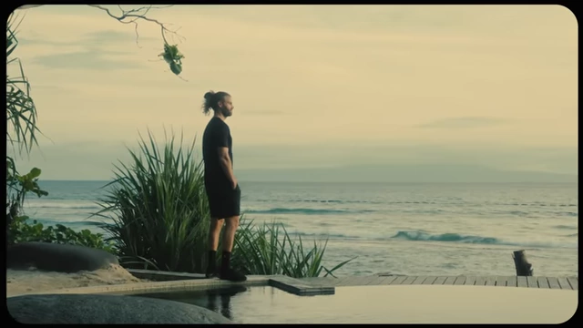 The speaker standing on a boardwalk overlooking the ocean, embodying the "freedom" core feeling of his brand.