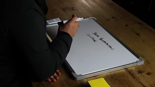 The speaker adding "culture" to a list on the whiteboard.
