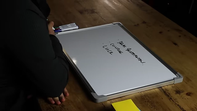 The speaker adding "luck" to his list of winning strategies on the whiteboard.