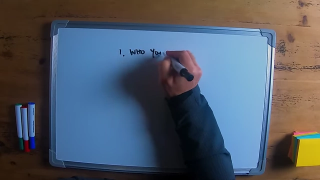 The speaker writing "who your customer is" on a whiteboard, emphasizing the first step in marketing.
