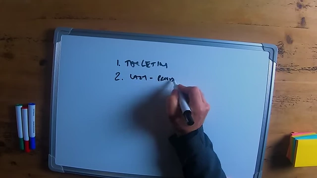 The speaker writing "lazy - provide them detail" on a whiteboard, explaining how to approach journalists for PR.