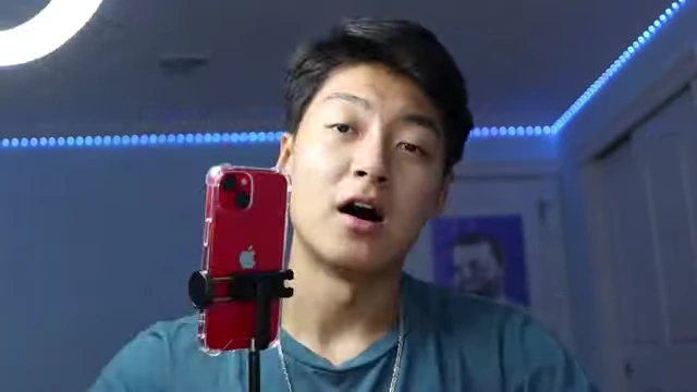 The speaker demonstrating his filming setup with a smartphone on a mini tripod and a ring light.