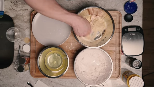 Coating a chicken tender evenly with crushed Rice Krispies
