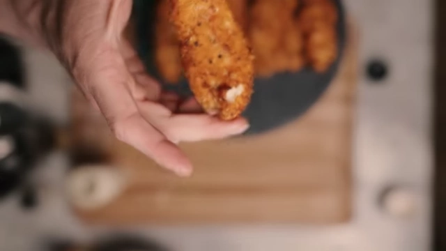 A cooked chicken tender being dipped into the low-calorie sauce