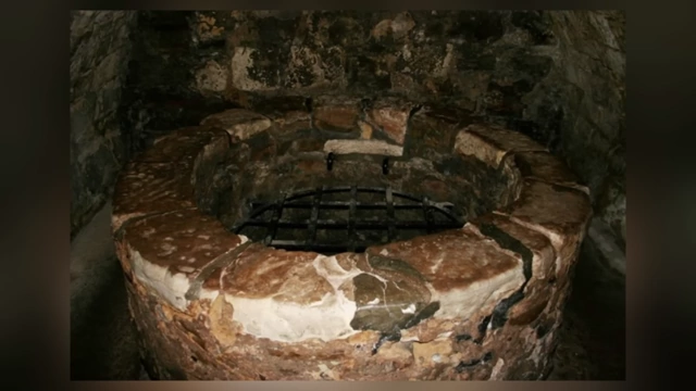 A stone "bottle dungeon," a deep, circular pit with a barred opening, similar to an oubliette, used for imprisonment.