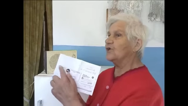 An elderly woman holding a bill, highlighting the issue of low tariffs for wired radio service.