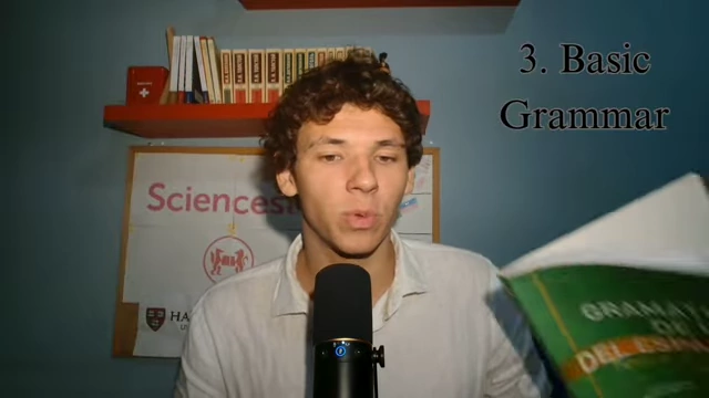 The speaker presents a Spanish grammar book, highlighting its usefulness for structured learning.