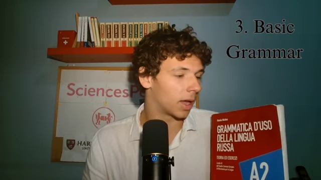 The speaker holds up a book titled "Grammatica d'uso della lingua russa", an Italian textbook for Russian grammar.