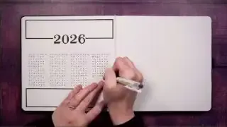 Hand drawing a cyclic calendar spread in a journal for the year 2026