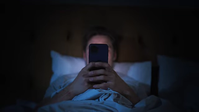 A person using a smartphone in bed at night