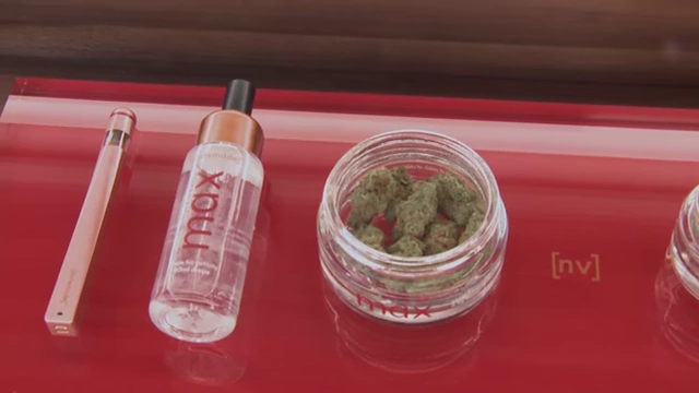 Various cannabis products displayed in a store, including jars of flower and vape pens