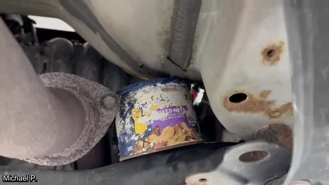 A container of mixed nuts resting precariously next to the exhaust pipe.