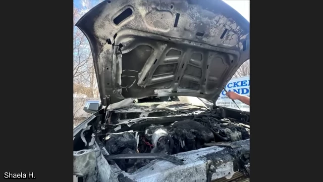 A broader view of the fire-damaged truck with its hood open.