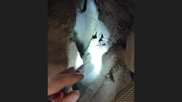 Hard-packed dirt accumulated under a vehicle, visible with a flashlight.