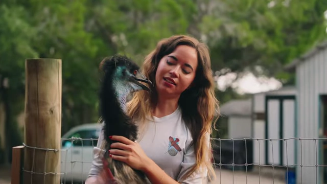 Maya Higa holding an emu, demonstrating ethical and caring interaction with an animal ambassador.
