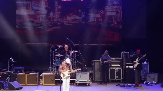 An older musician plays an electric guitar on stage, symbolizing art as a timeless conduit for understanding.