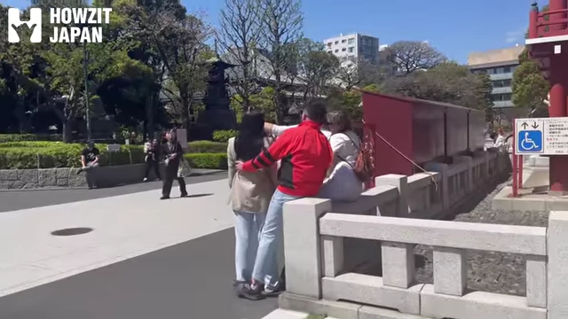 Tourists sitting on the stone fence outside Senso-ji temple, illustrating improper etiquette