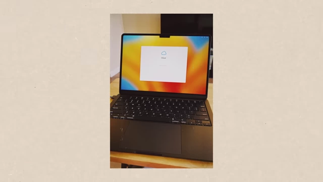 A black M2 MacBook Air with an iCloud login prompt on its screen.