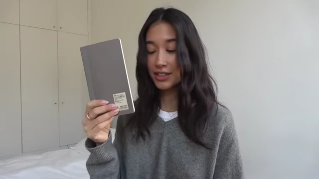 The presenter holds up a small, practical notebook for daily tasks.