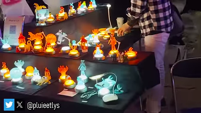 A booth showcasing intricate glow-in-the-dark and illuminated art pieces, creating a unique atmosphere in the Low Light Area.