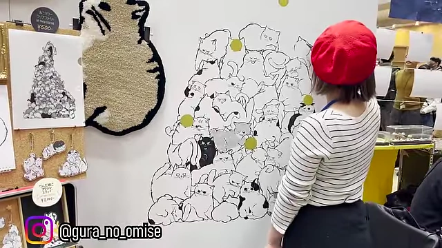 An artist creating a large mural of a pile of adorable cats.