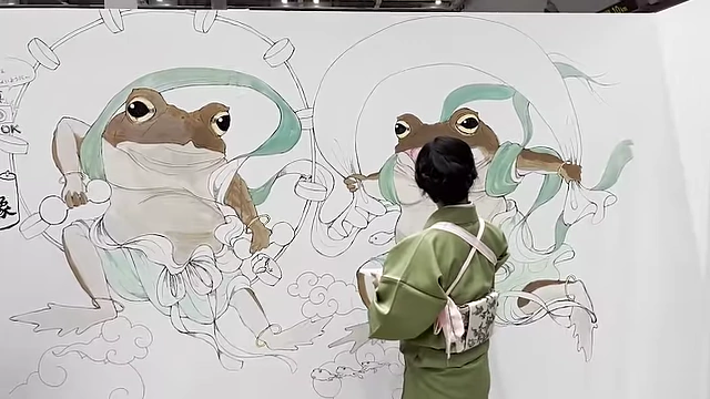 An artist painting a large mural of dancing frogs in traditional attire.