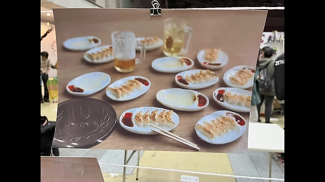 A photograph of miniature gyoza plates and beer for scale, showcasing the realism of the clay art.