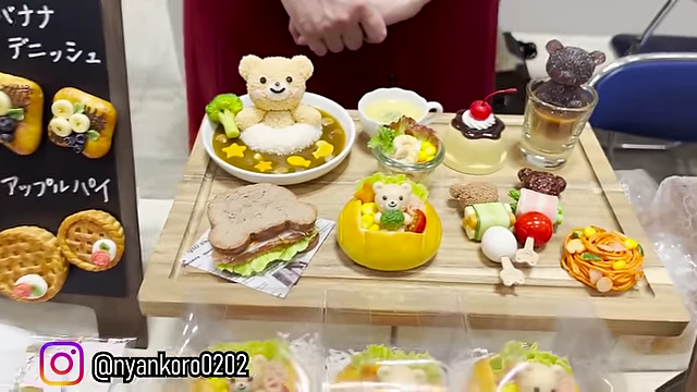 Cute bento box-style food art, featuring a teddy bear rice dish and various side items.