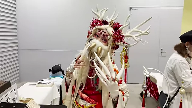 An attendee dressed in an elaborate, horned costume with intricate facial detailing.