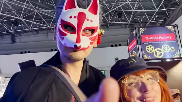 An attendee wearing a traditional Kitsune mask, posing with June, Emirichu's friend.