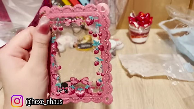 A pink, strawberry-themed photo card holder with a dangling charm.