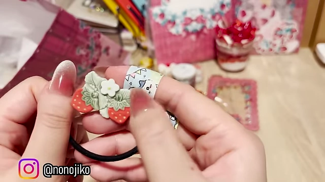 A hair tie adorned with a cute strawberry clay charm.