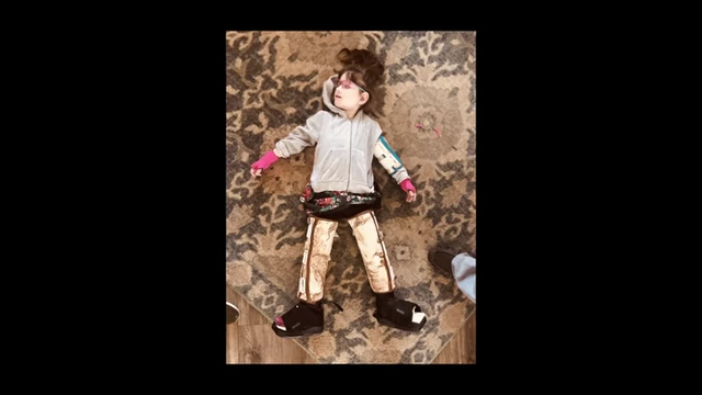 McSwee's sister lies on the floor, unable to walk, highlighting the severity of her quadriplegic cerebral palsy.