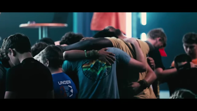 Camp attendees gather, some with hands raised or heads bowed in prayer during a worship session.